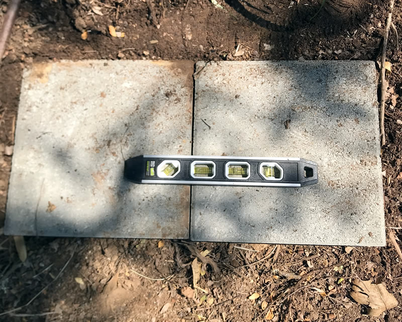Leveling tool sitting on concrete stepping stone