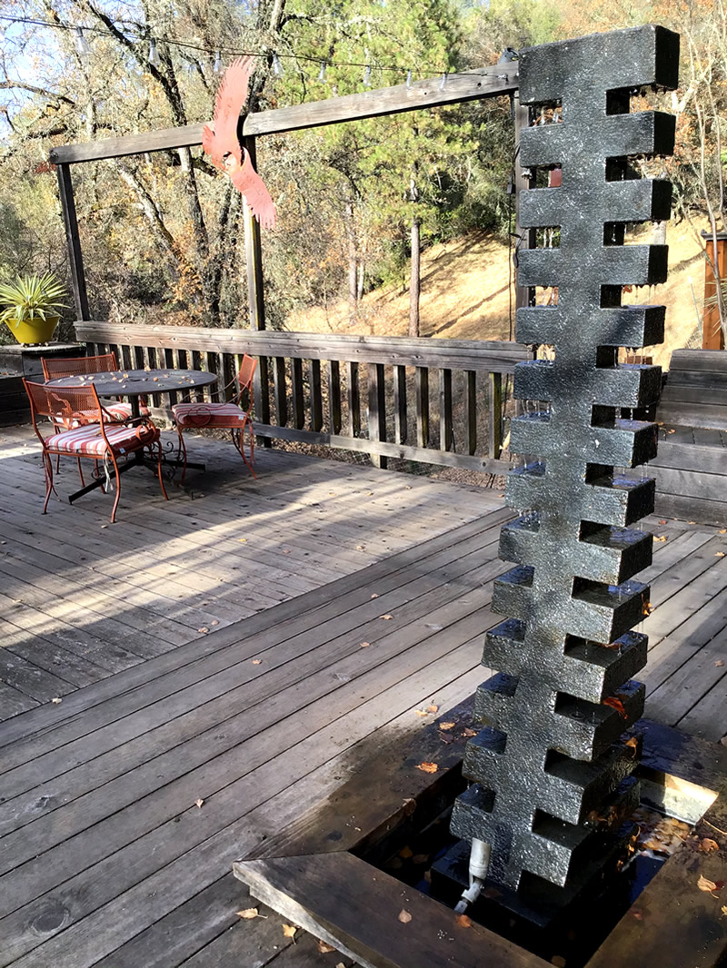 Tall ladder-like fountain on a deck, water cascading