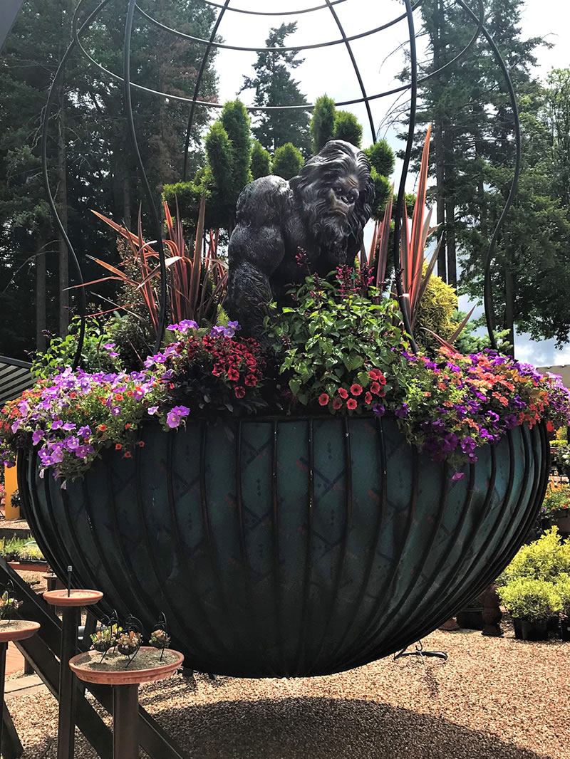 Giant hanging basket with plants, flowers and sculpture of Sasquatch