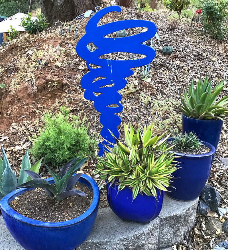 Succulents in blue pots with blue swirl garden sculpture