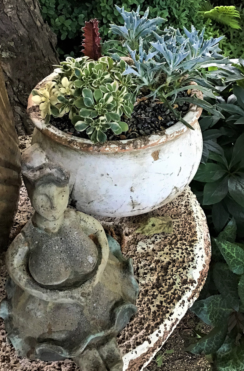 Succulents in white pot with small figure of seated lady