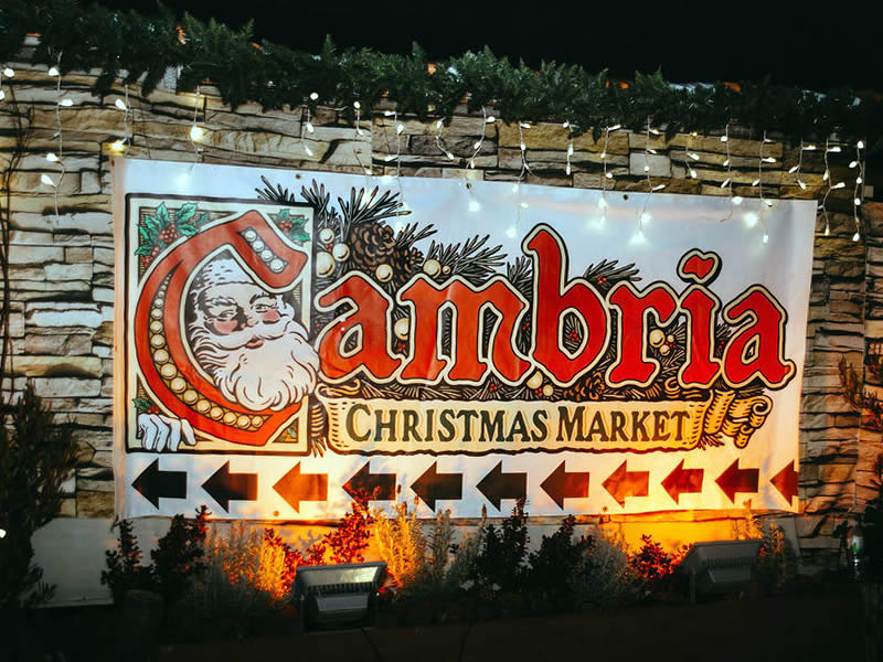 Outdoor sign at night reading Cambria Christmas Market