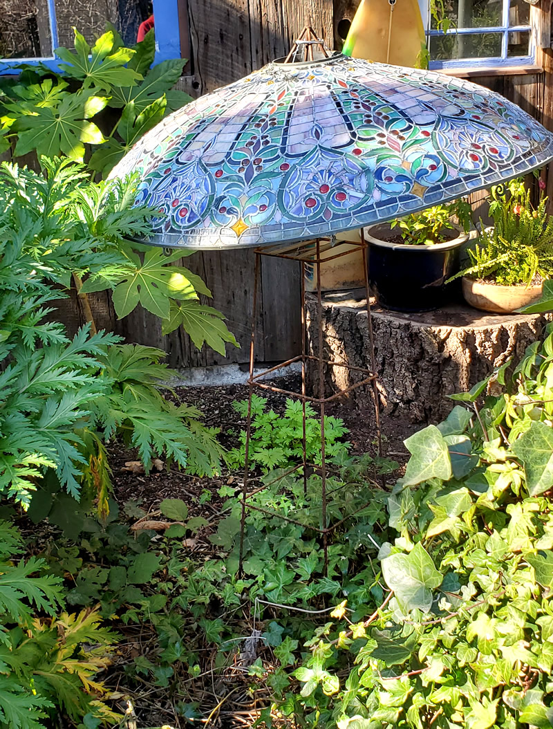 Garden object, a stained glass umbrella standing over plants