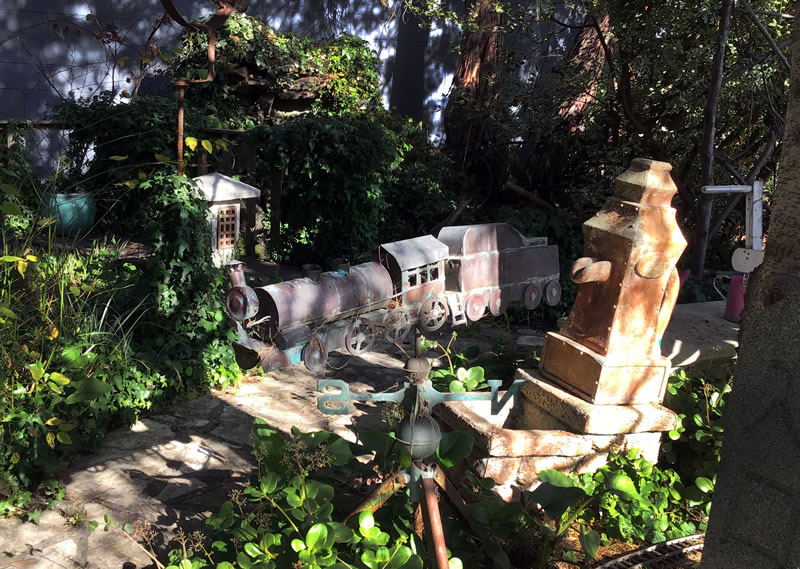 Garden art, a metal train along a narrow path between garden plants