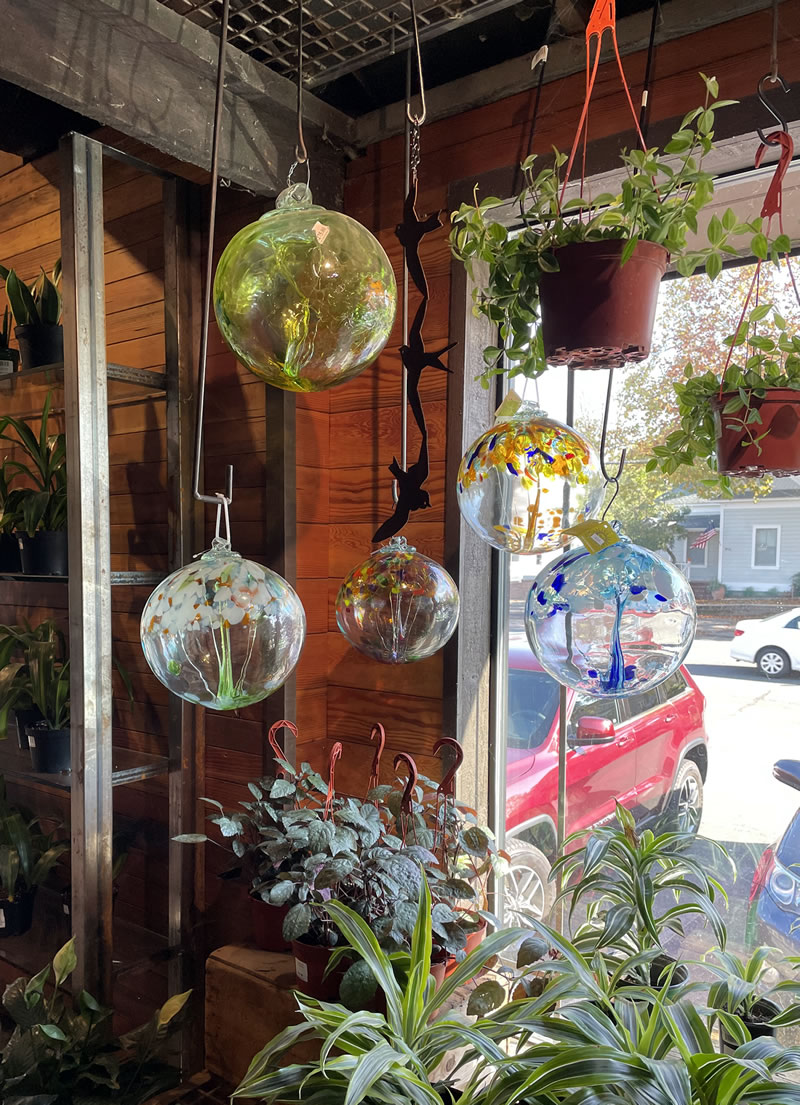 Gift shop window interior with hanging glass orbs.