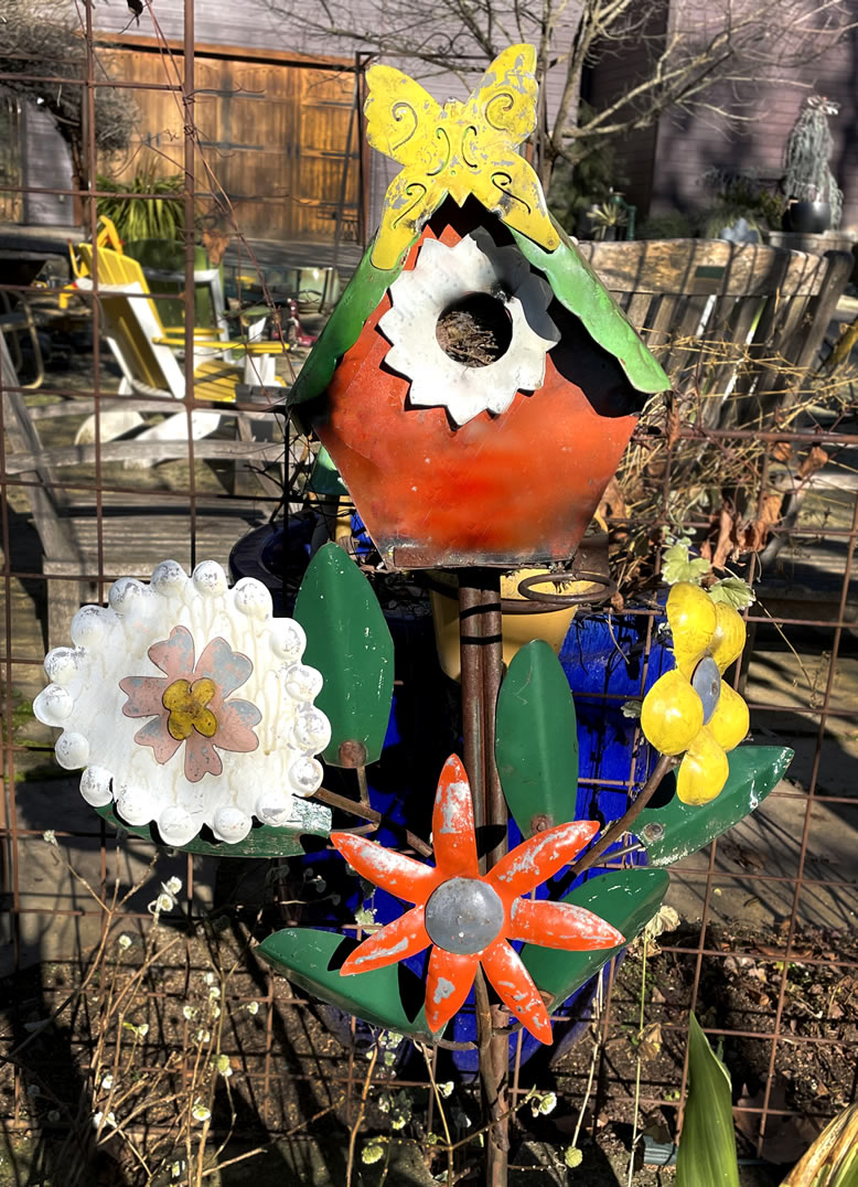 Metal bird house and flowers in bright colors .