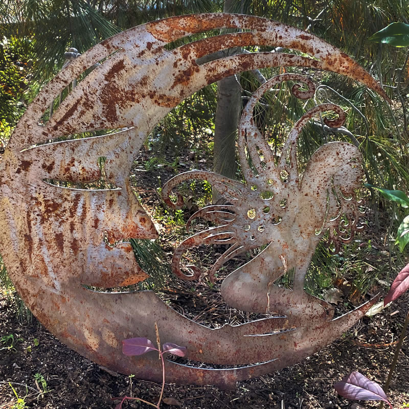 Metal cutout of fairy sitting on moon shape.